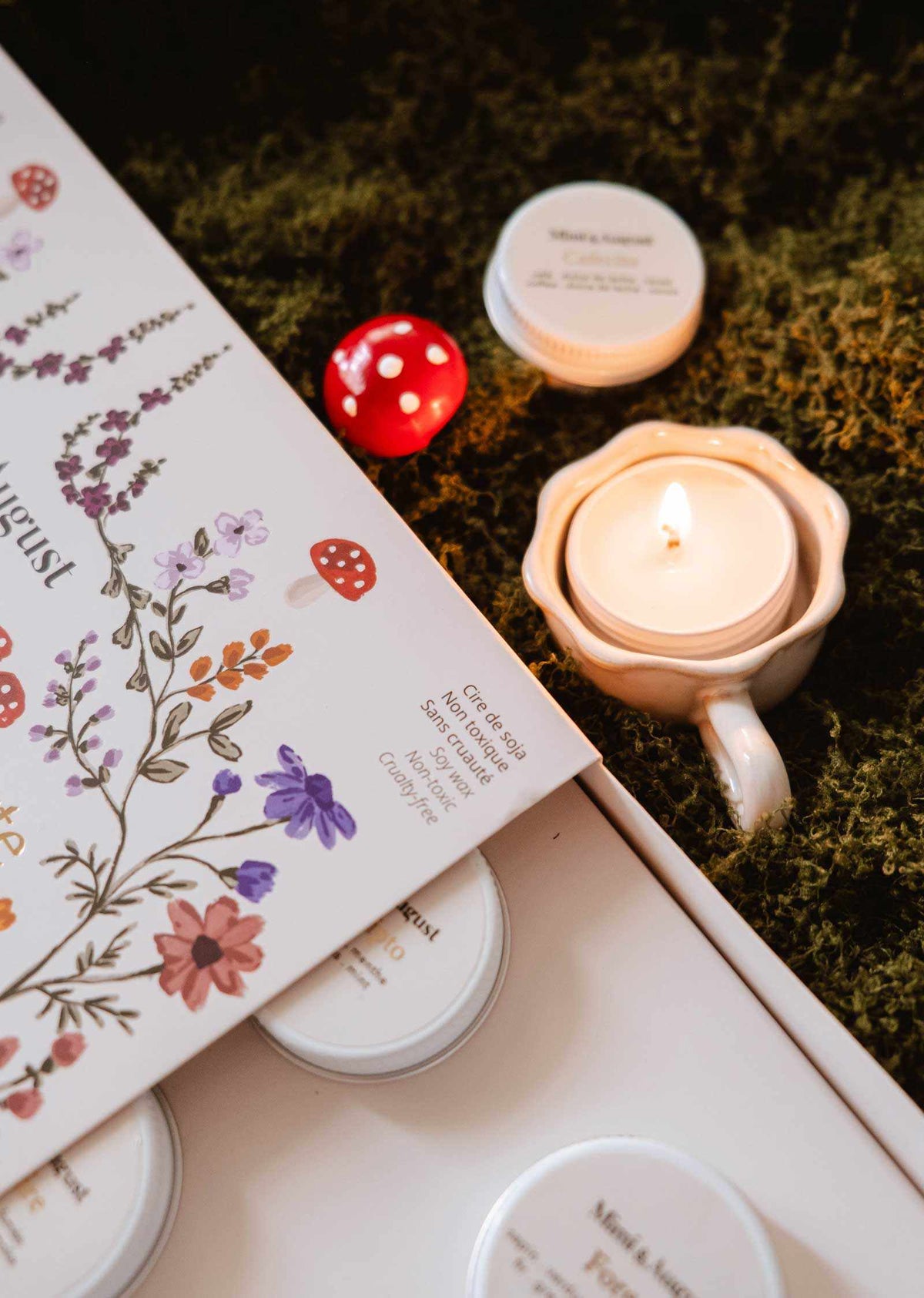 Fall candle gift set with white soy tealights, floral illustrated packaging, and a lit cream ceramic holder