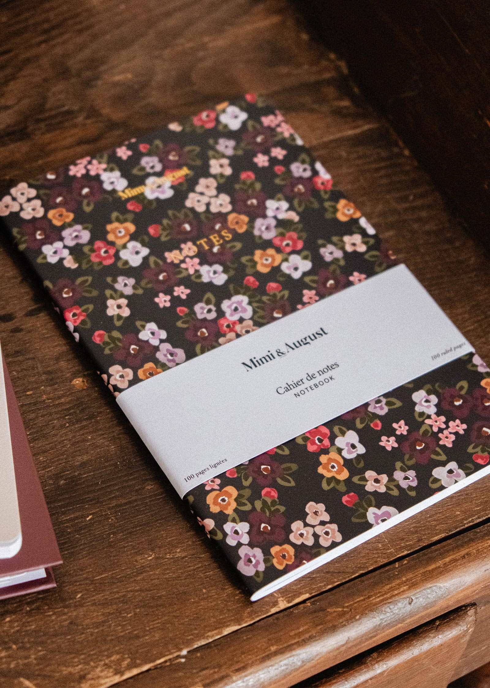Fields of Flower floral notebook by Mimi & August, with floral illustrations, resting on a wooden surface.