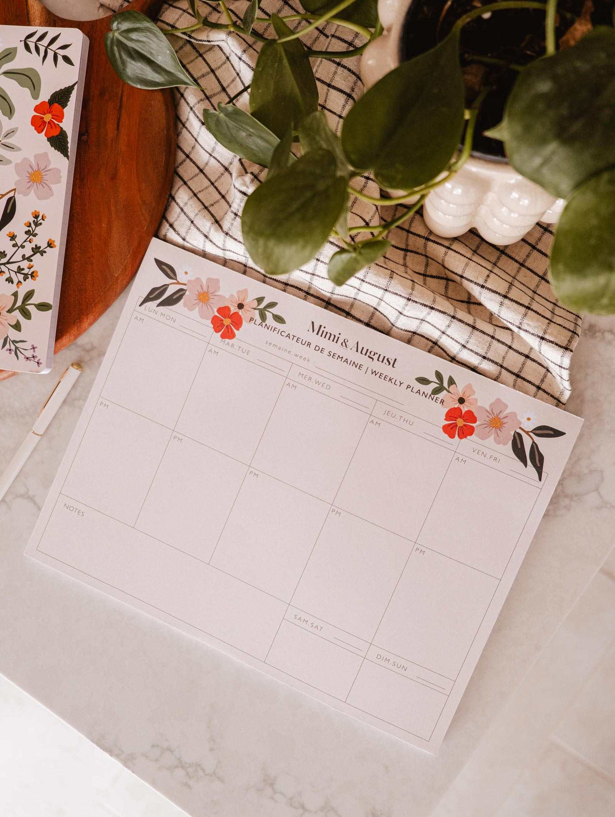 An eco-friendly Flower Bomb - Weekly Planner desk by Mimi & August with a plant next to it.