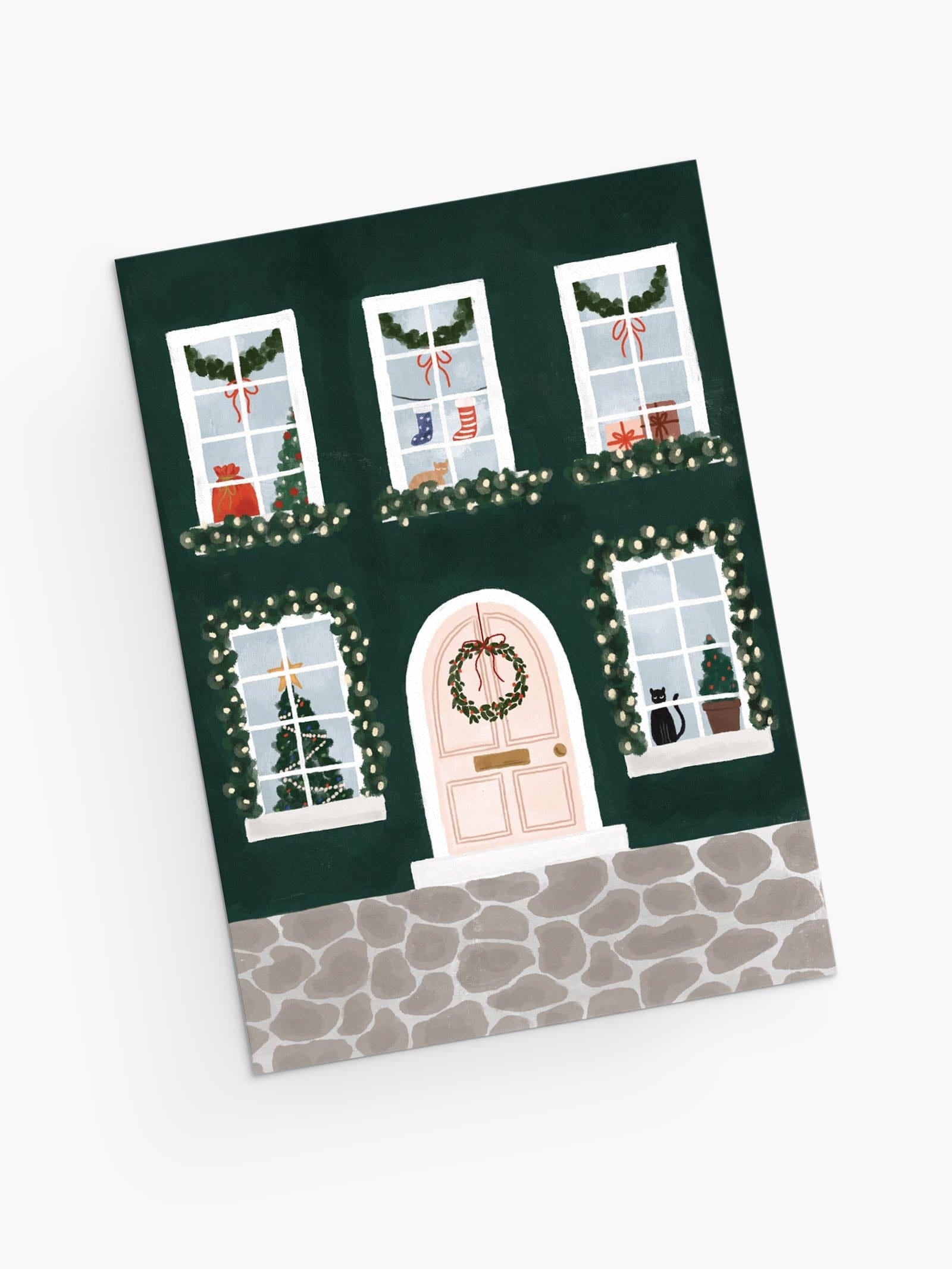 Cute Christmas greeting card featuring a home with christmas wreath at the door, and kitties, socks and trees through the windows. By Mimi & August
