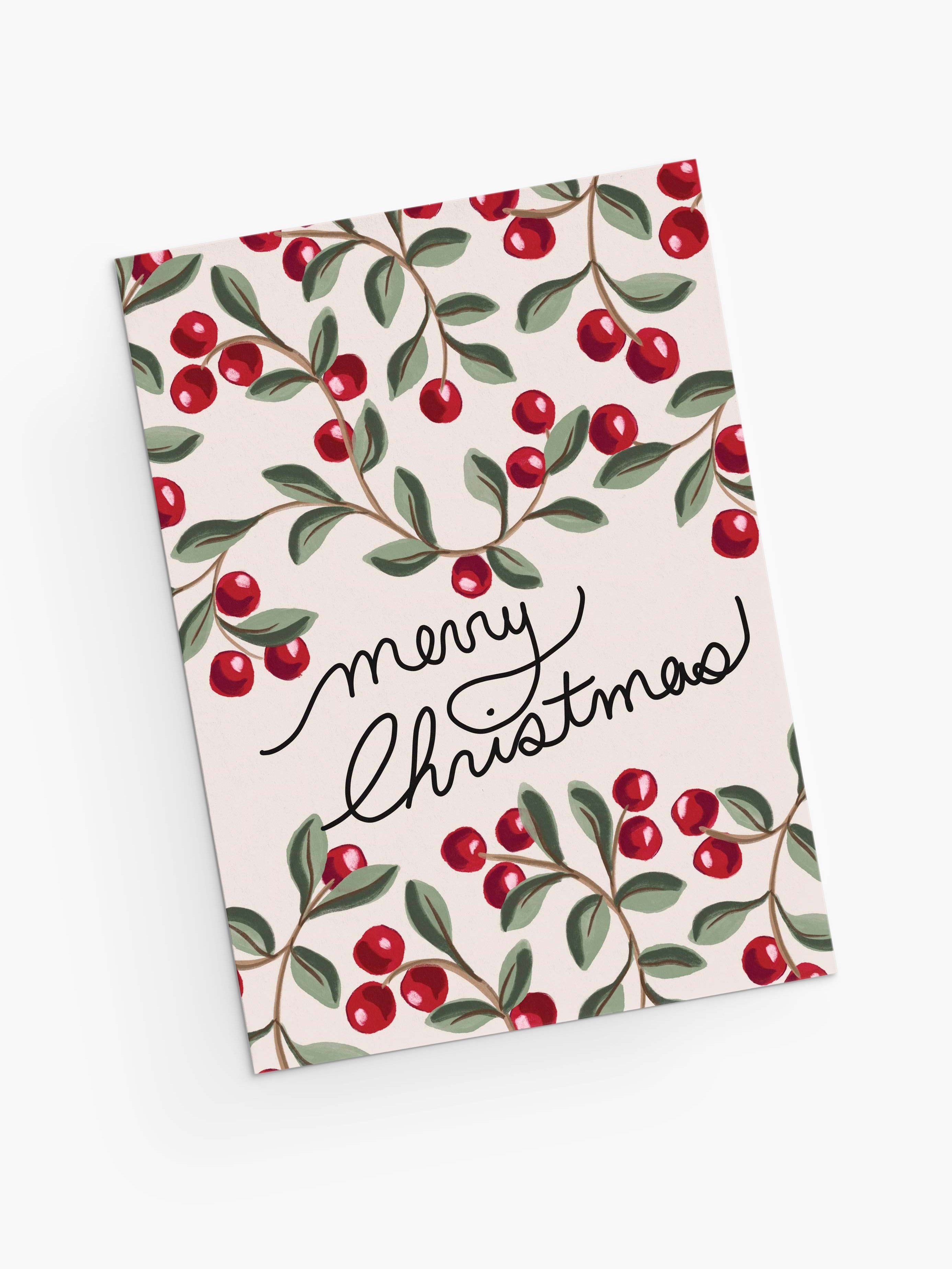 The Merry Christmas Greeting Card by Mimi & August features a red berry and green leaf pattern, "Merry Christmas" in handwritten text, is printed on recycled paper, and comes blank inside for your own message.
