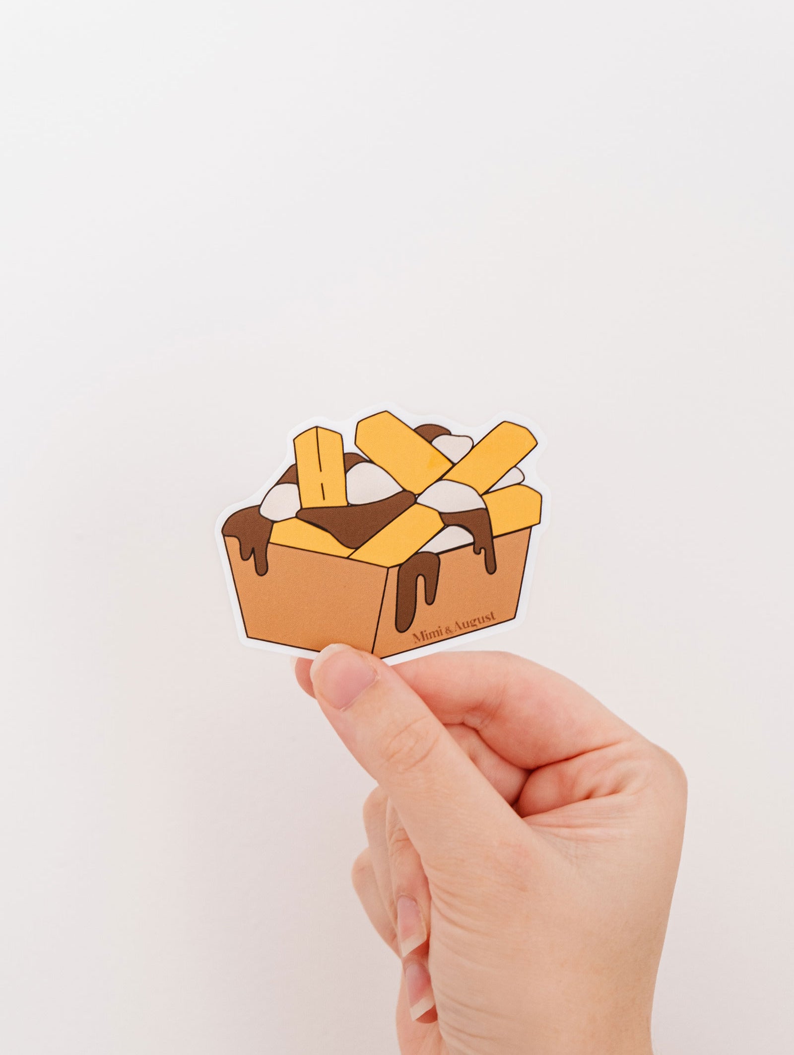 A person proudly displaying a box of Mimi & August Quebec-style poutine, with a Vinyl Sticker on it.