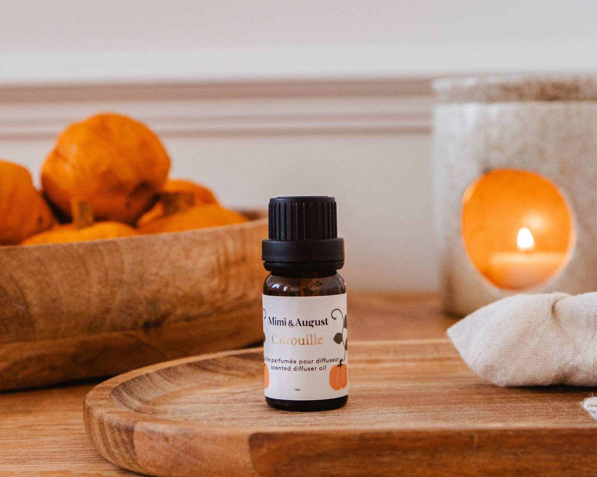 Pumpkin spice scented oil bottle with autumn leaves and warm spices background