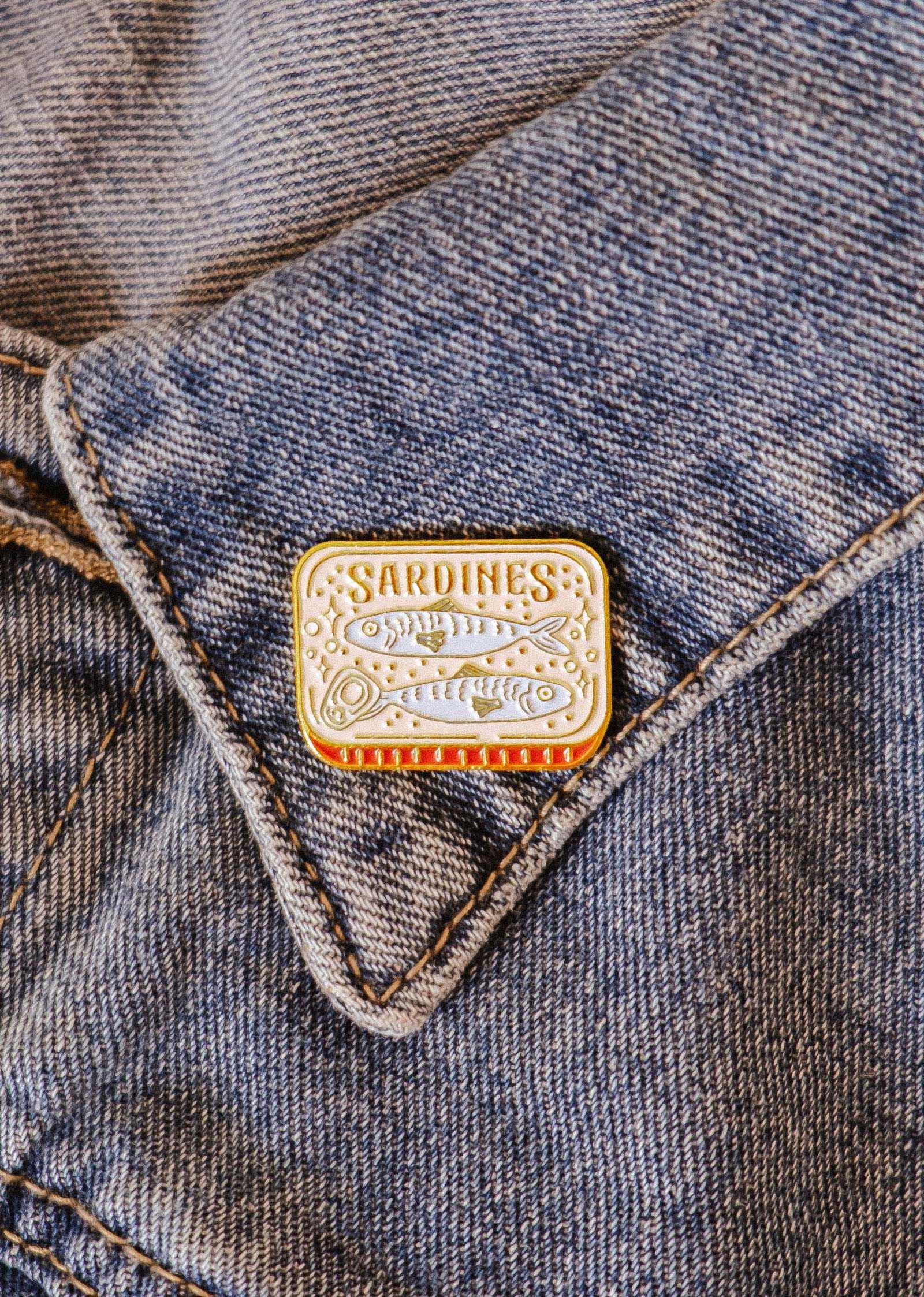 The Cozy Sardines Enamel Pin by Mimi & August, designed in Montreal, adds a touch of personality and charm to your jean pocket.
