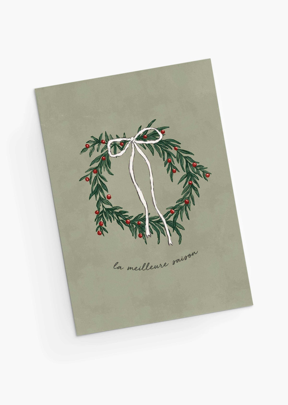 The Best Season Christmas Greeting Card by Mimi & August features an illustrated wreath with a white bow and red berries, “la meilleure saison” text on muted green, is blank inside for your message, and printed on recycled paper.