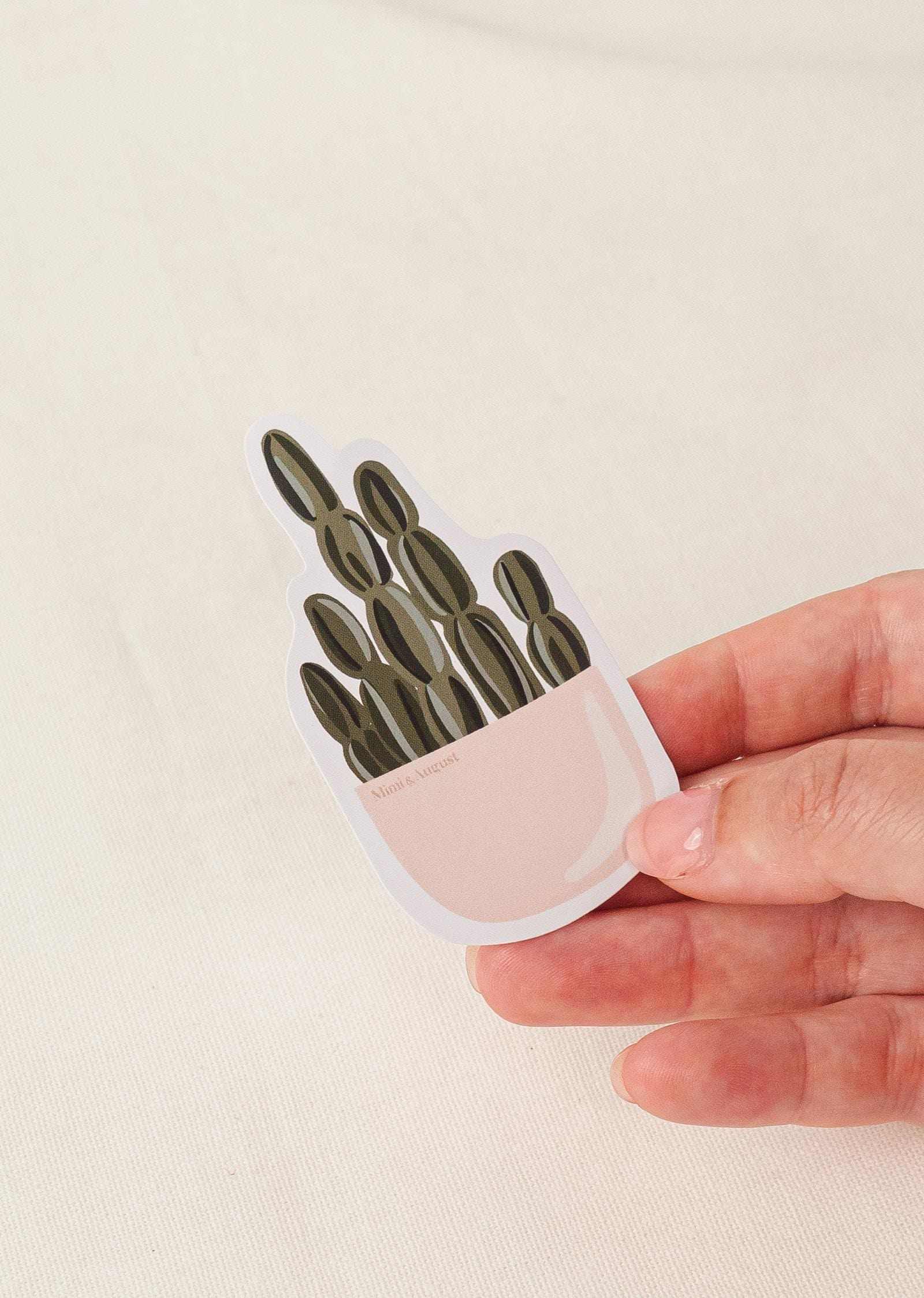 Hand holding Cactus Party vinyl sticker with cactus design and white border on beige background