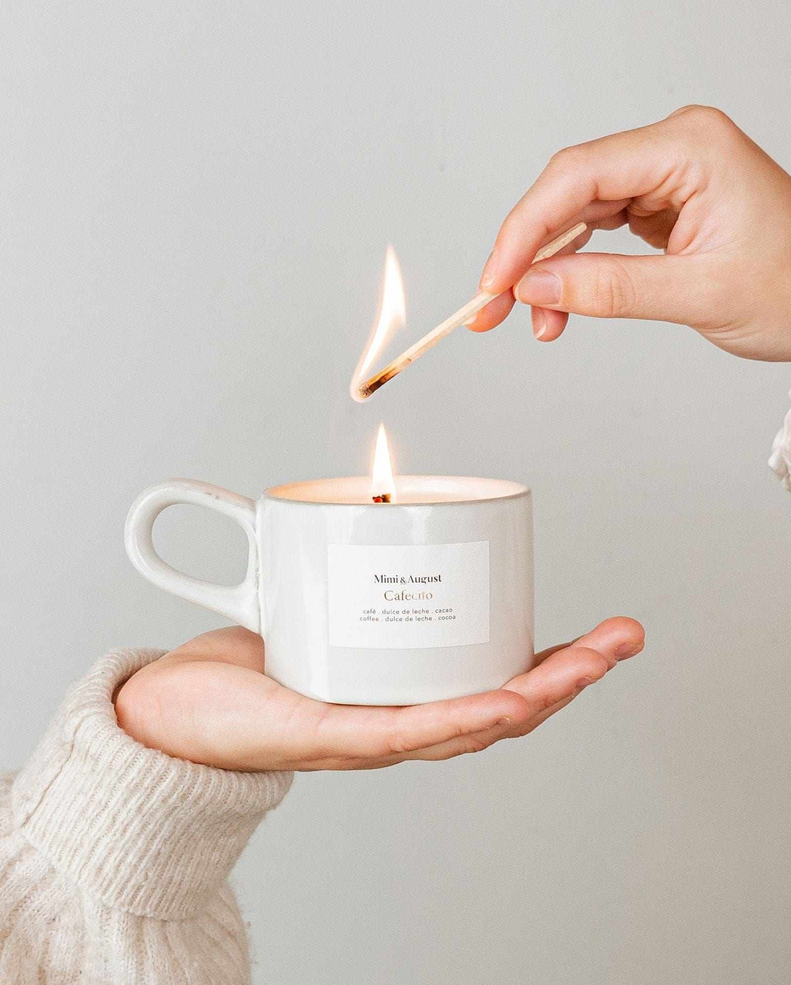 Hand lighting a reusable candle in a white coffee mug with coffee scent and cozy atmosphere