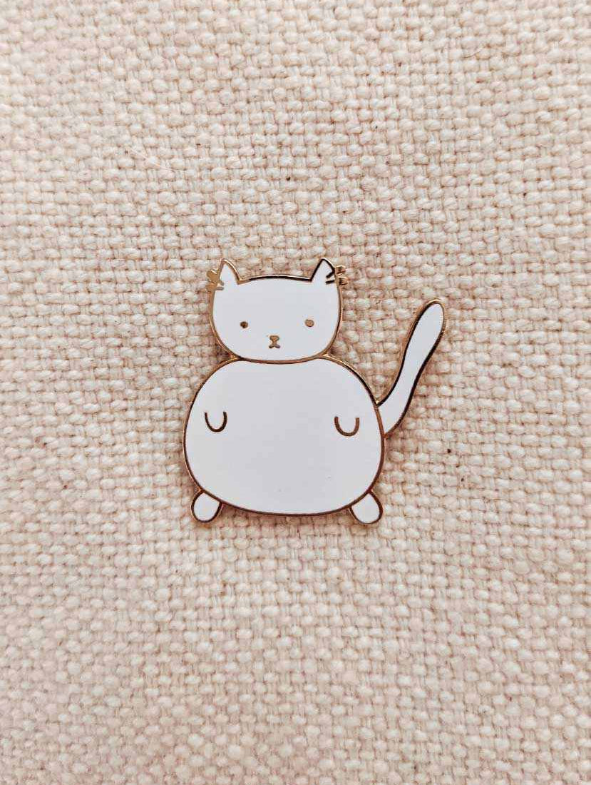 Charlotte Enamel Pin small white cat enamel pin with gold tone brass on fabric background