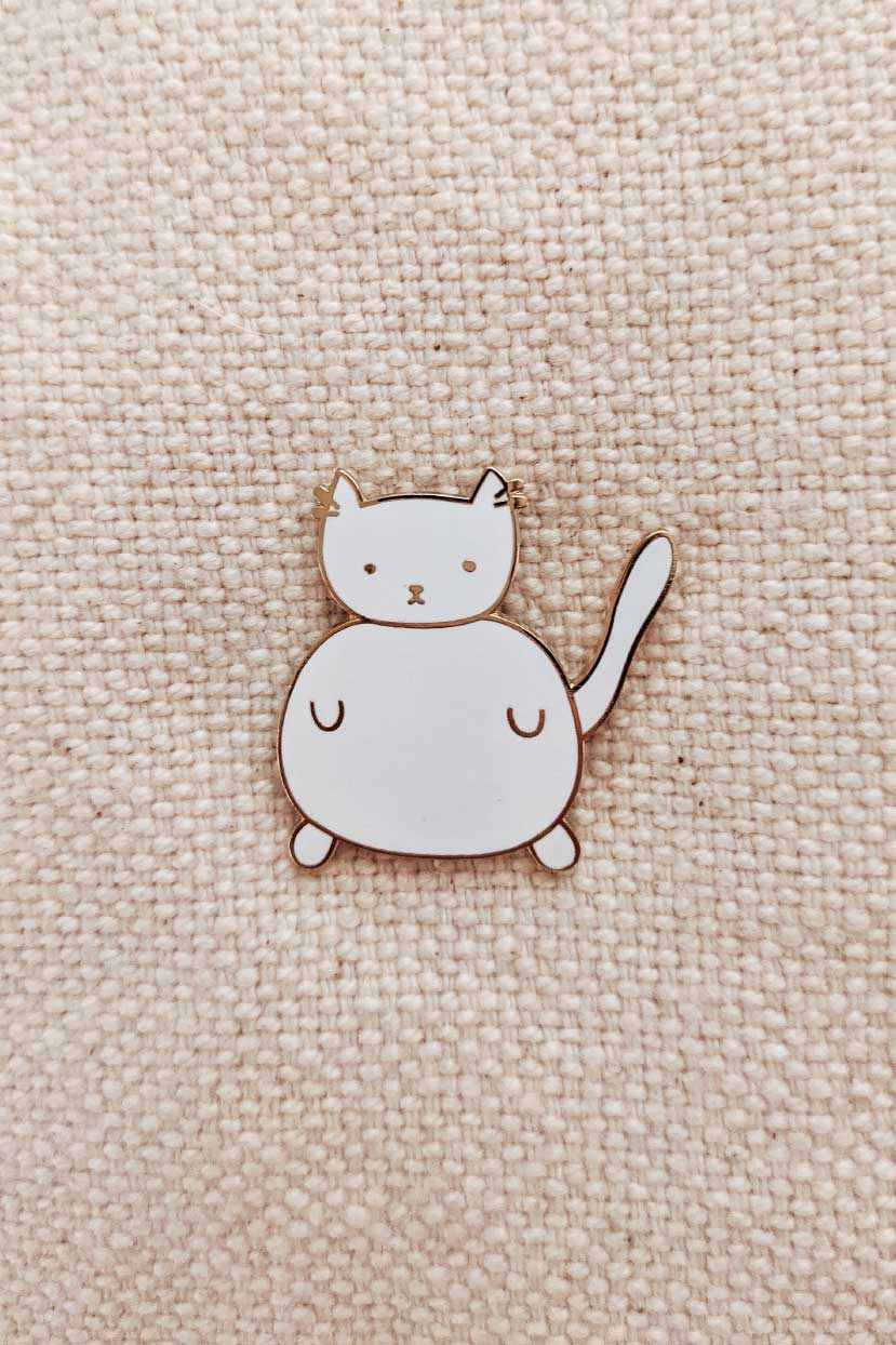 Charlotte Enamel Pin small white cat enamel pin with gold tone brass on fabric background