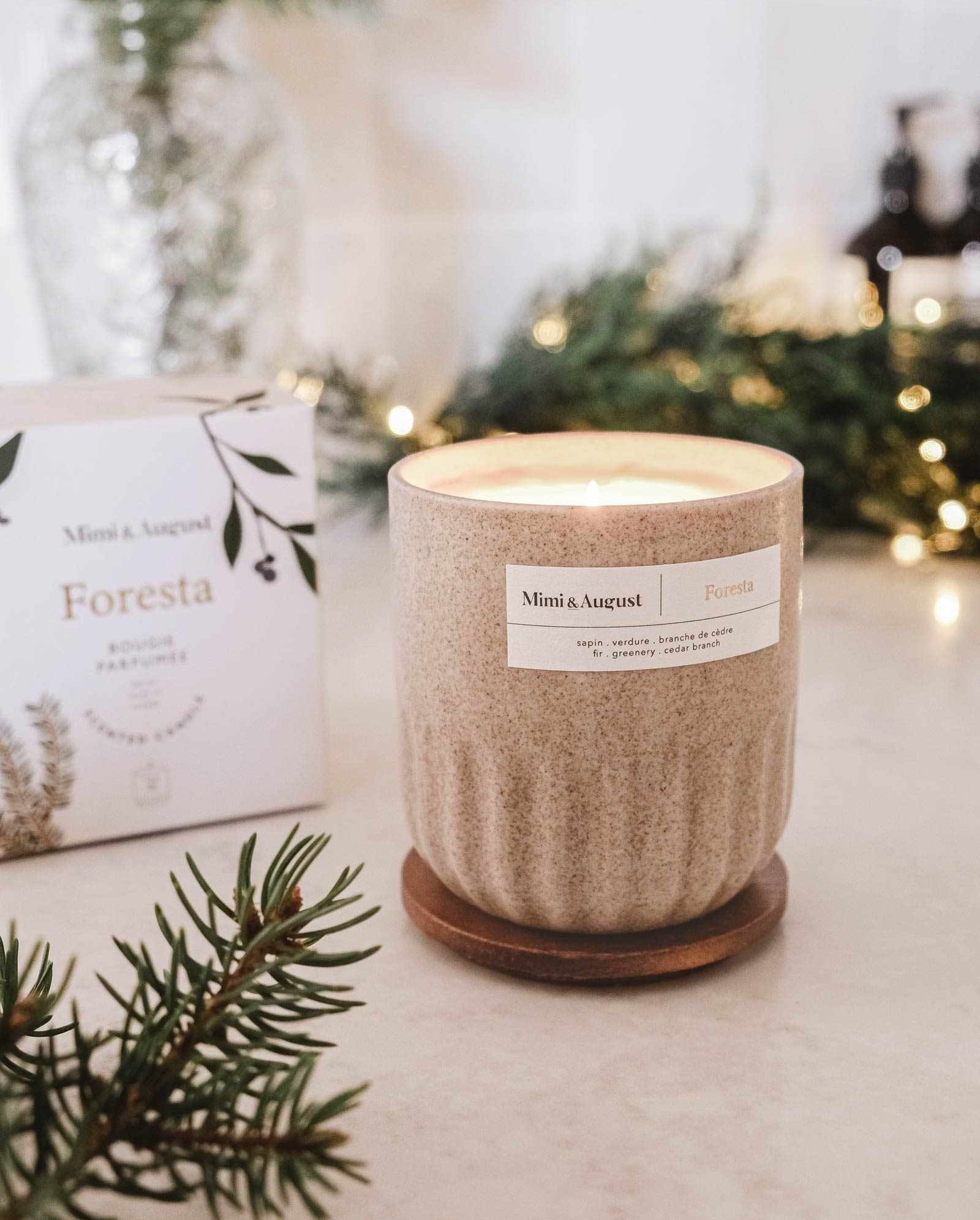 Reusable fir tree candle in ceramic cup with soft glowing flame and festive greenery background