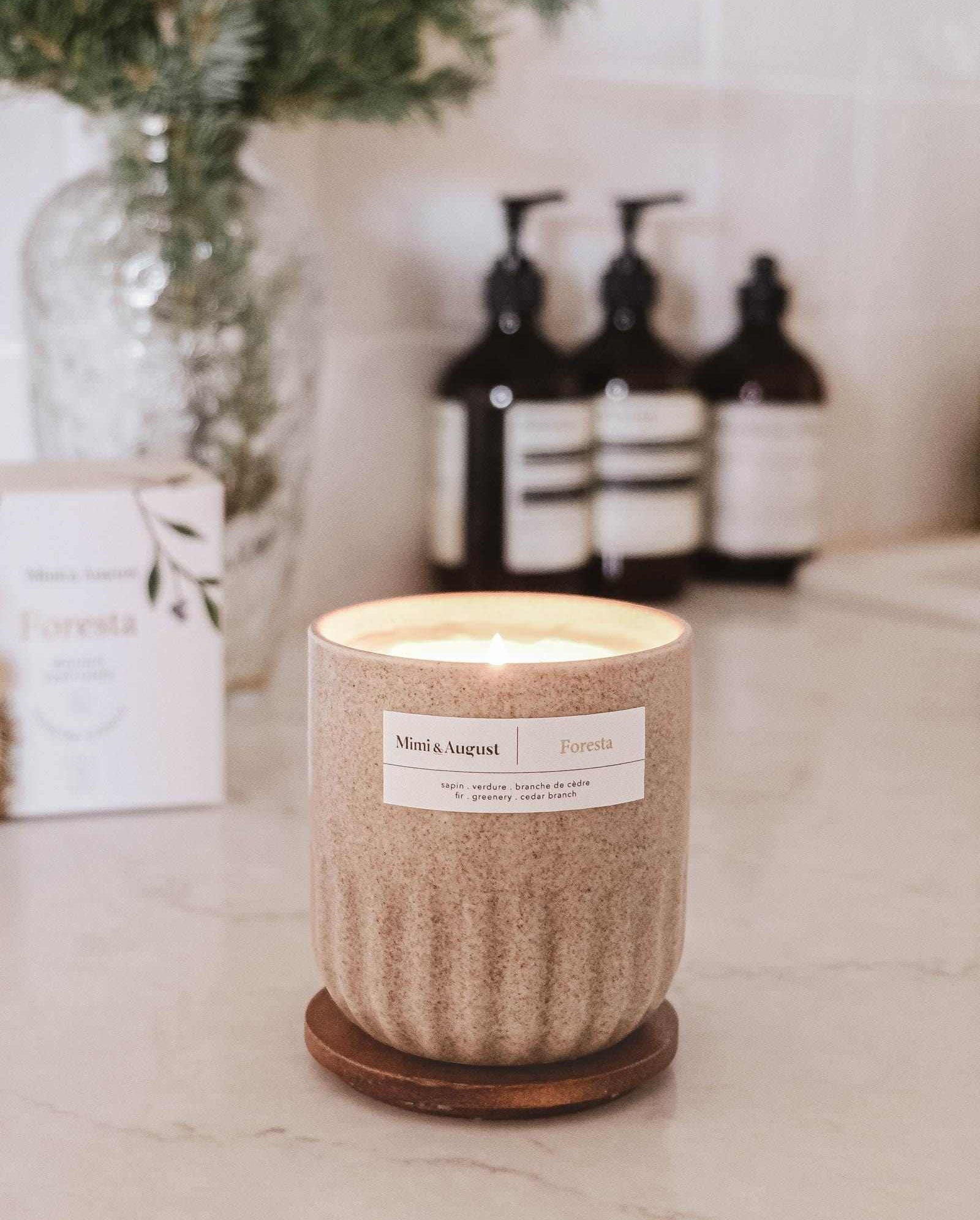 Reusable fir tree candle Foresta in ceramic cup on kitchen counter with blurred background.