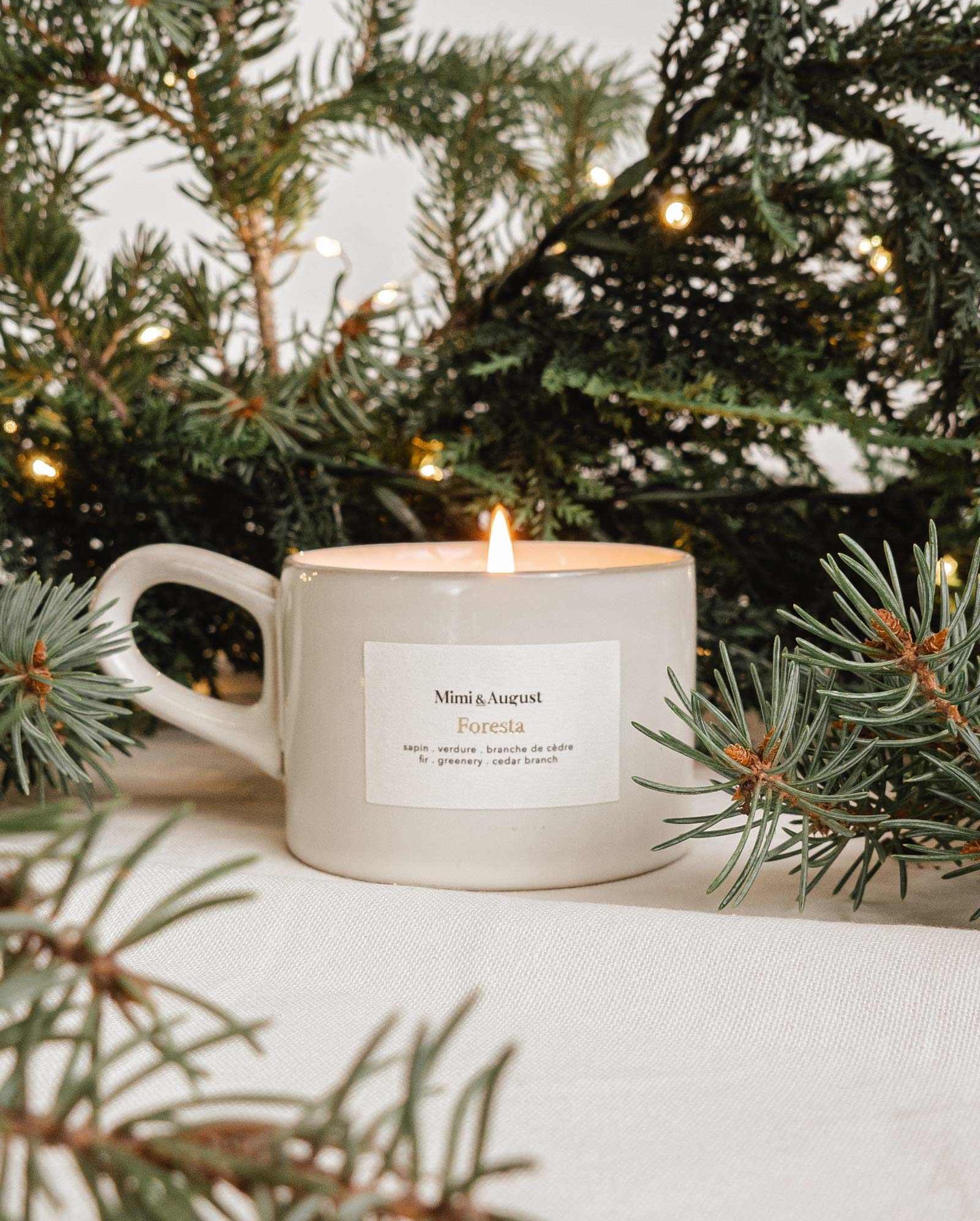 Foresta fir tree candle in a speckled gray handle cup with forest fir branches and warm lights background