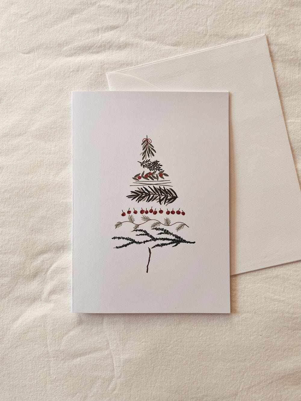 Minimal Christmas tree greeting card on recycled matte cardstock with white envelope and compostable packaging