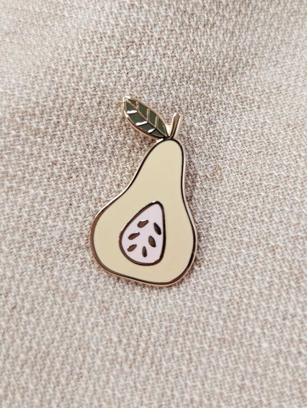 Pear enamel pin in gold tone brass with green leaf design on fabric background