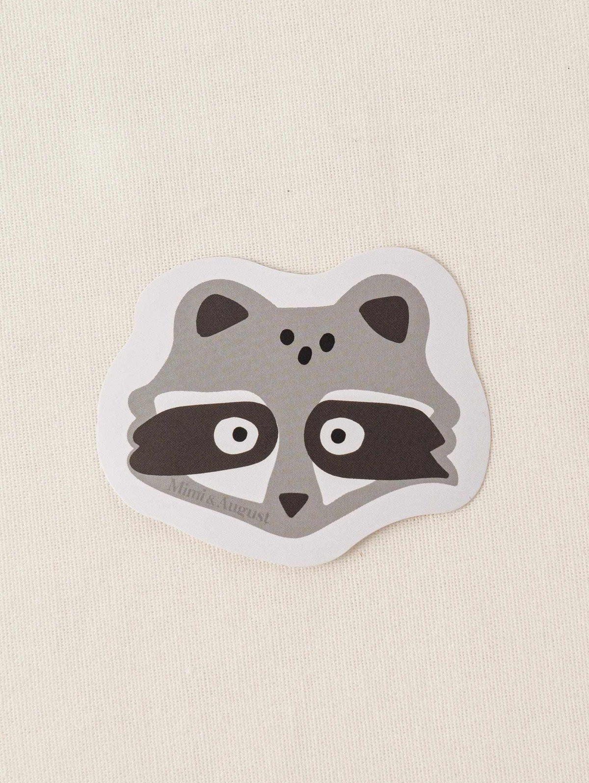Cute vinyl sticker of a raccoon face with matte finish and white border