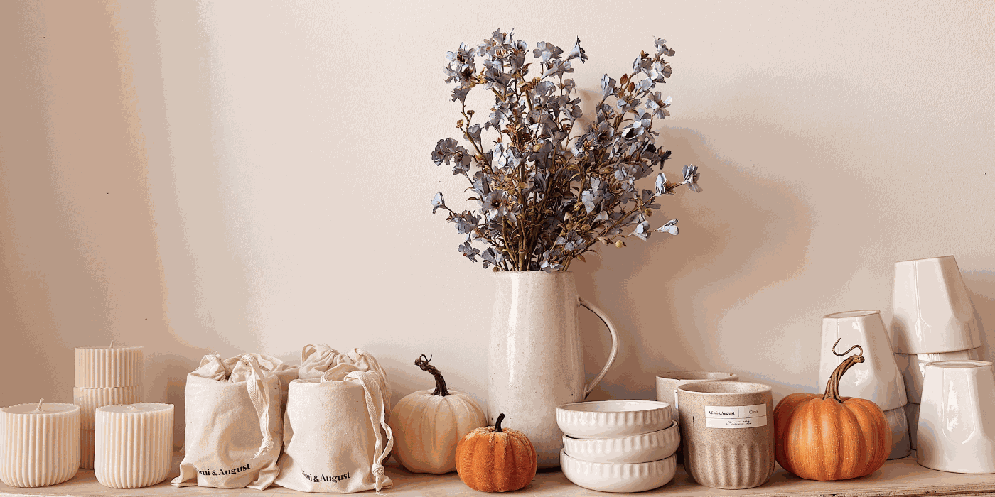 Soy candles vs paraffin comparison featuring beige ceramic soy candles, textured bowls, orange pumpkins, and dried floral arrangement