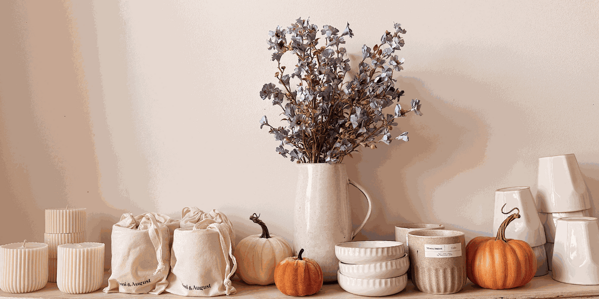 Soy candles vs paraffin comparison featuring beige ceramic soy candles, textured bowls, orange pumpkins, and dried floral arrangement