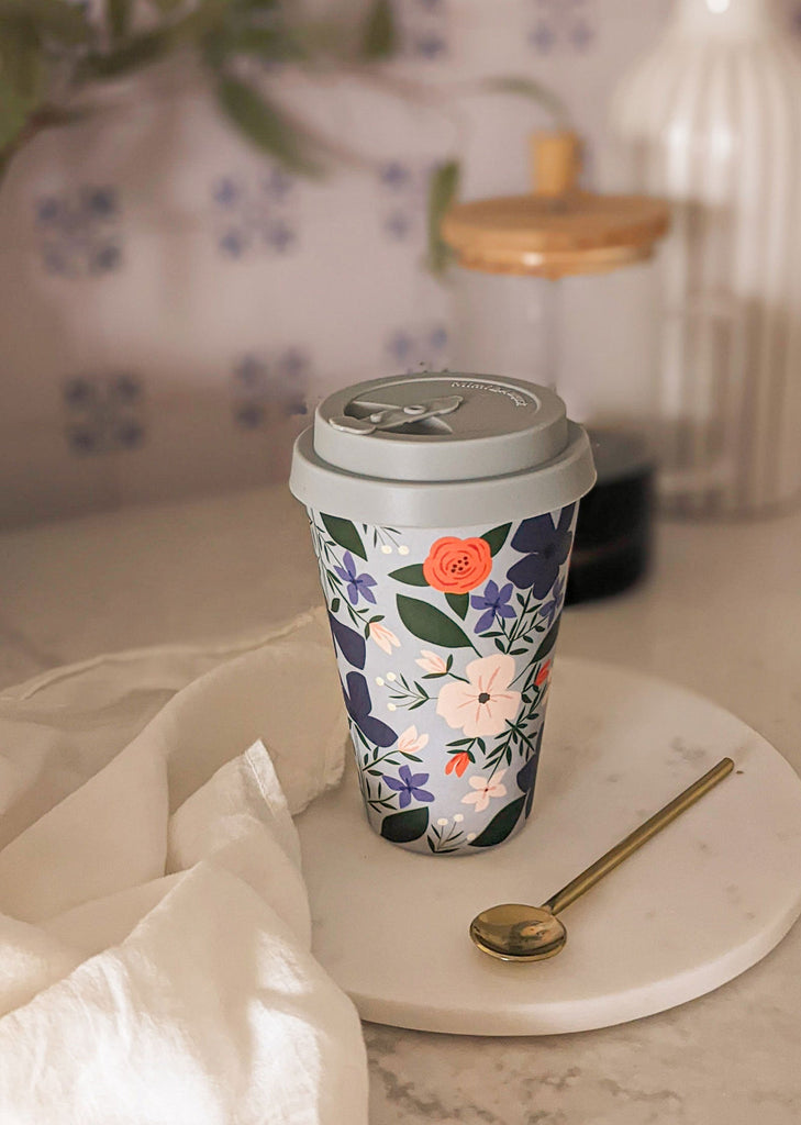 Une tasse à café sur une assiette blanche ornée de fleurs.