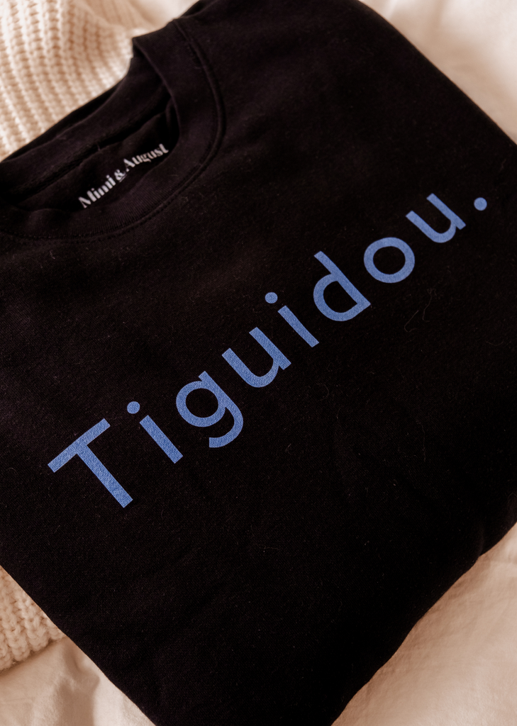 Un sweat-shirt respirant Mimi & August Tiguidou noir avec le mot tiguidou dessus.