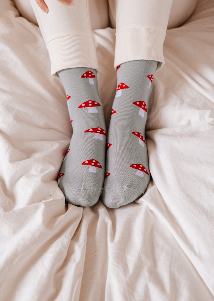 Pair of light blue socks with little red and white mushrooms, by Mimi & August.