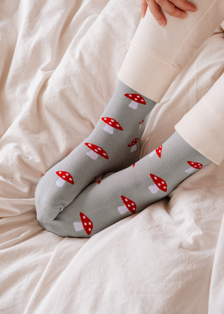 A woman wearing a pair of light blue Little Mushrooms socks from Mimi & August.