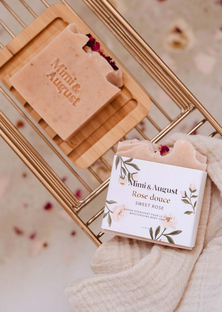 Handmade Mimi & August Sweet Rose Bar Soap with rose petals on a wooden rack, displaying branding and ingredients, moisturizes and nourishes the skin.