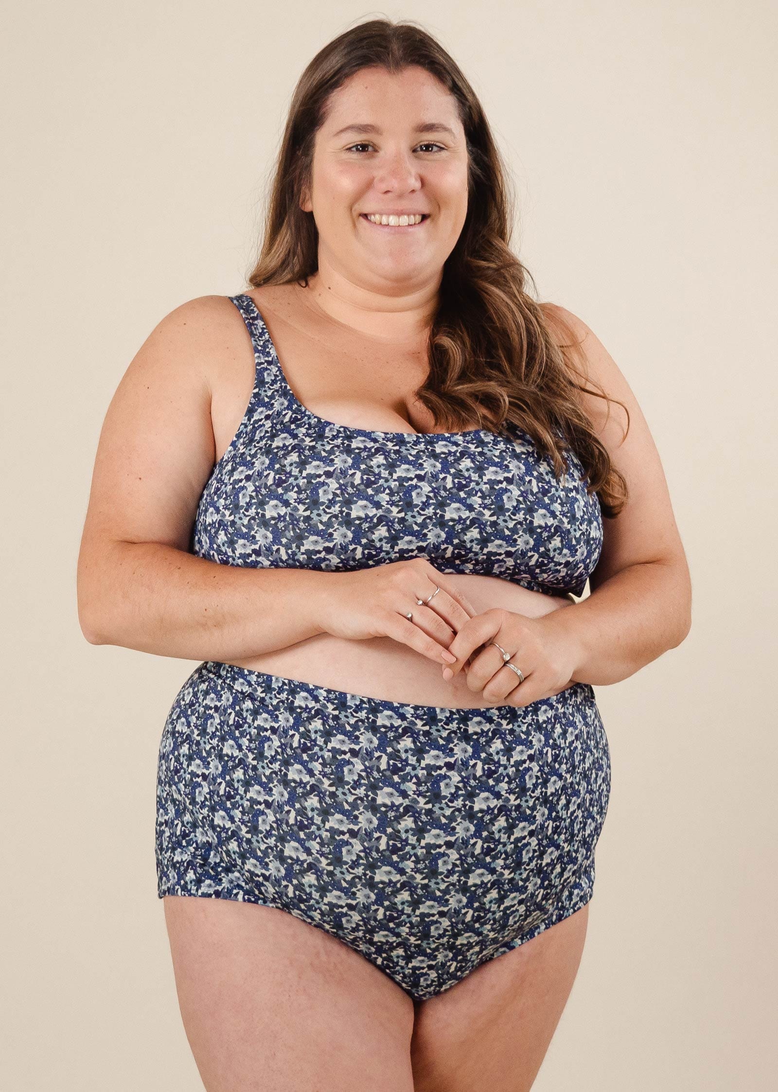 A woman in comfiest bikini bottom in a vibrant blue floral design smiles effortlessly.