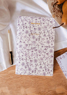The Blossom - Notebook by Mimi & August, labeled "NOTES," rests on a wooden surface beside a pen, pears, and a white cloth—ideal as a lined journal for capturing your thoughts.