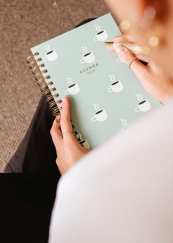 A coffee lover's dream, the Cafecito - Agenda 2025 by Mimi & August showcases a charming cover design featuring steaming coffee cups. This planner is perfectly organized and inspiring, inviting you to jot down your thoughts and plans for a productive year while enjoying your favorite brew.