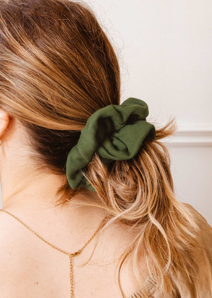 A woman wearing a color green scrunchie by mimi and august.
