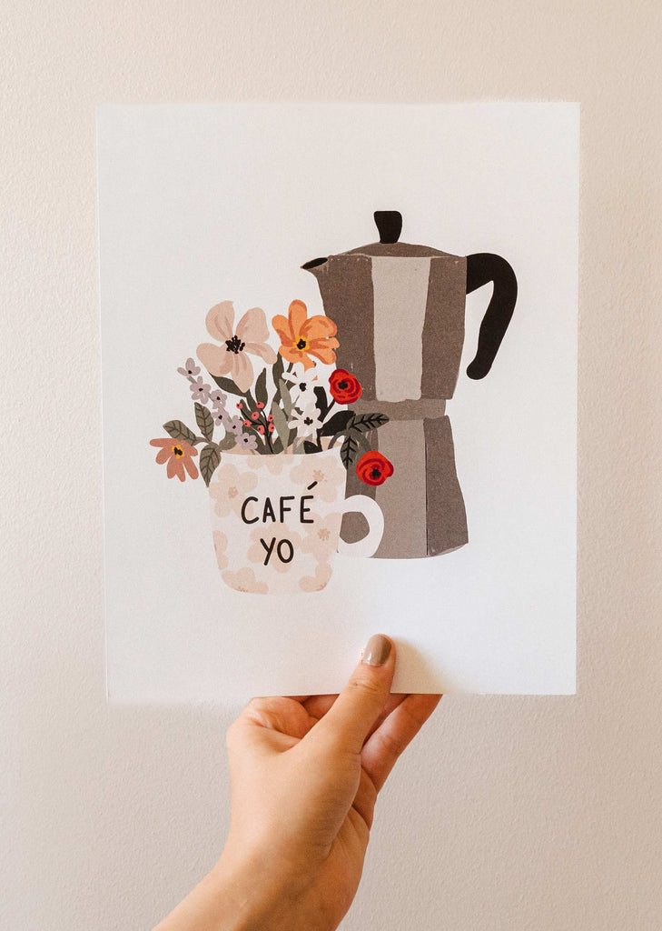A hand holding up a mimi and august Floral morning coffee pot and flowers.