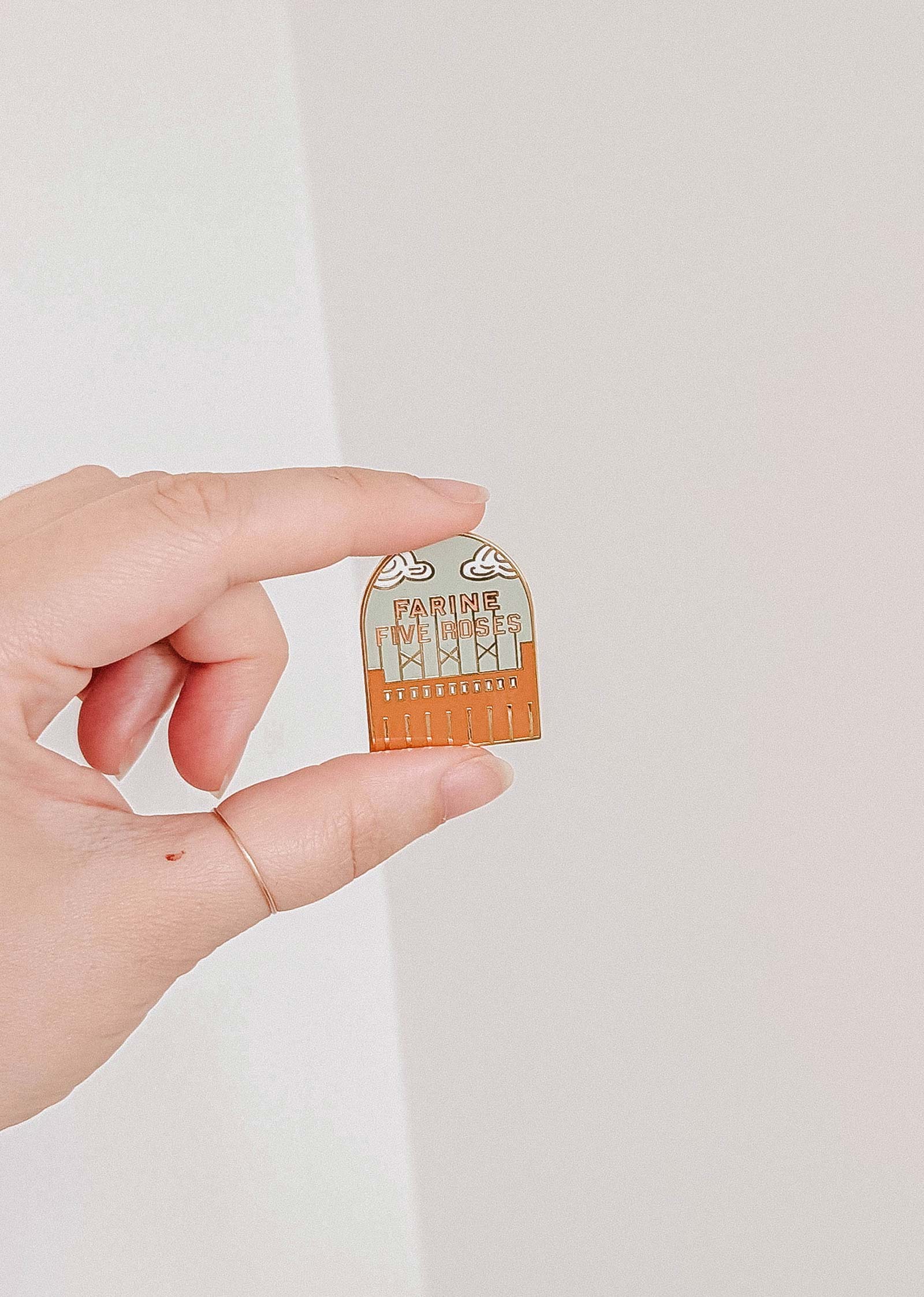 A hand holds the Mimi & August Flour & Roses Factory Enamel Pin, shaped like a brown comb with "Father, I've done my best" and a retro-inspired design.