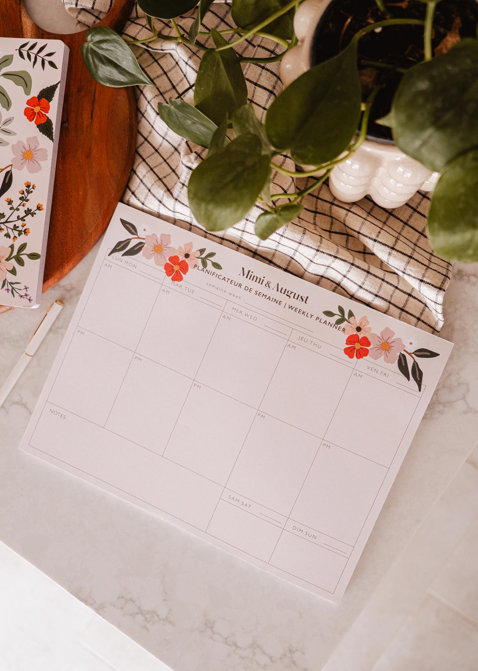 An eco-friendly Flower Bomb - Weekly Planner desk by Mimi & August with a plant next to it.