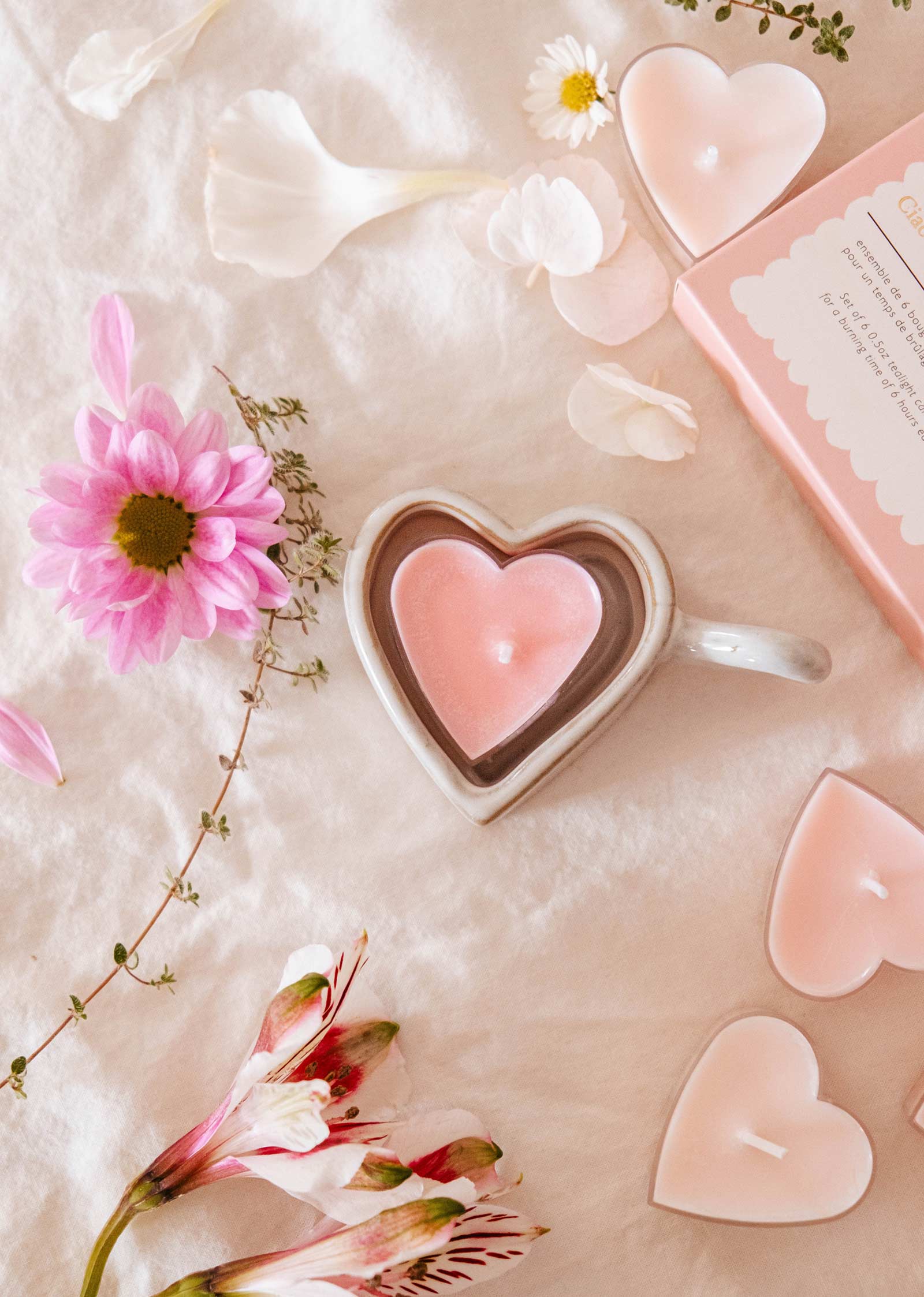 Le porte-bougies à réchaud en forme de coeur Heart & Glow et les bougies à réchaud Blush Hearts de Mimi & August sont associés à des fleurs sur un tissu blanc doux, rehaussé d'une boîte rose, pour un décor romantique parfait.