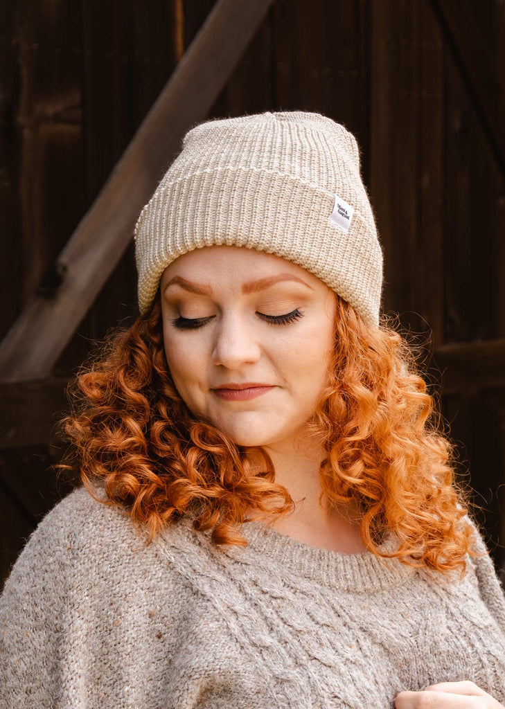 A woman with red hair wearing a mimi and august Ivory Cuffed Beanie.