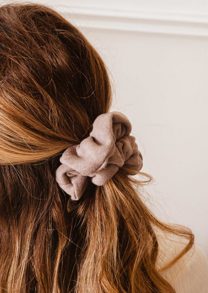 A woman wearing a color latte scrunchie by mimi and august.