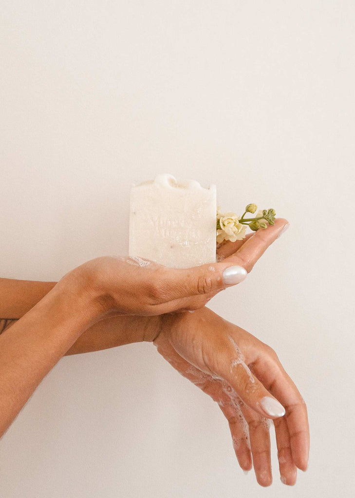 A woman's hands holding a Lavender & Sage soap bar with flowers on it.