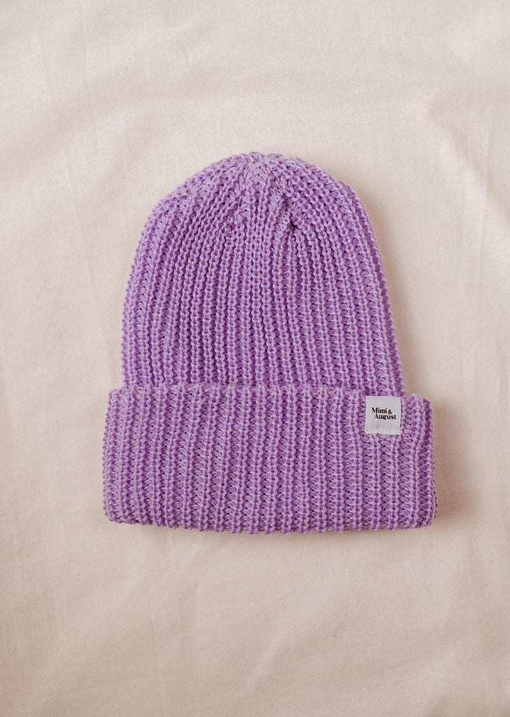 A Lilac Chunky Beanie on a white bed.