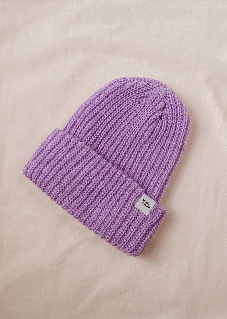  A Lilac Chunky Beanie by mimi and august laying on a bed.