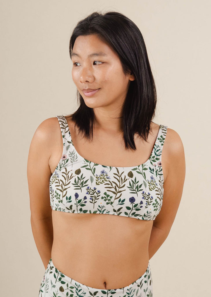 A woman in a Lima Herboria Bralette Bikini Top by mimi and august with a floral print.