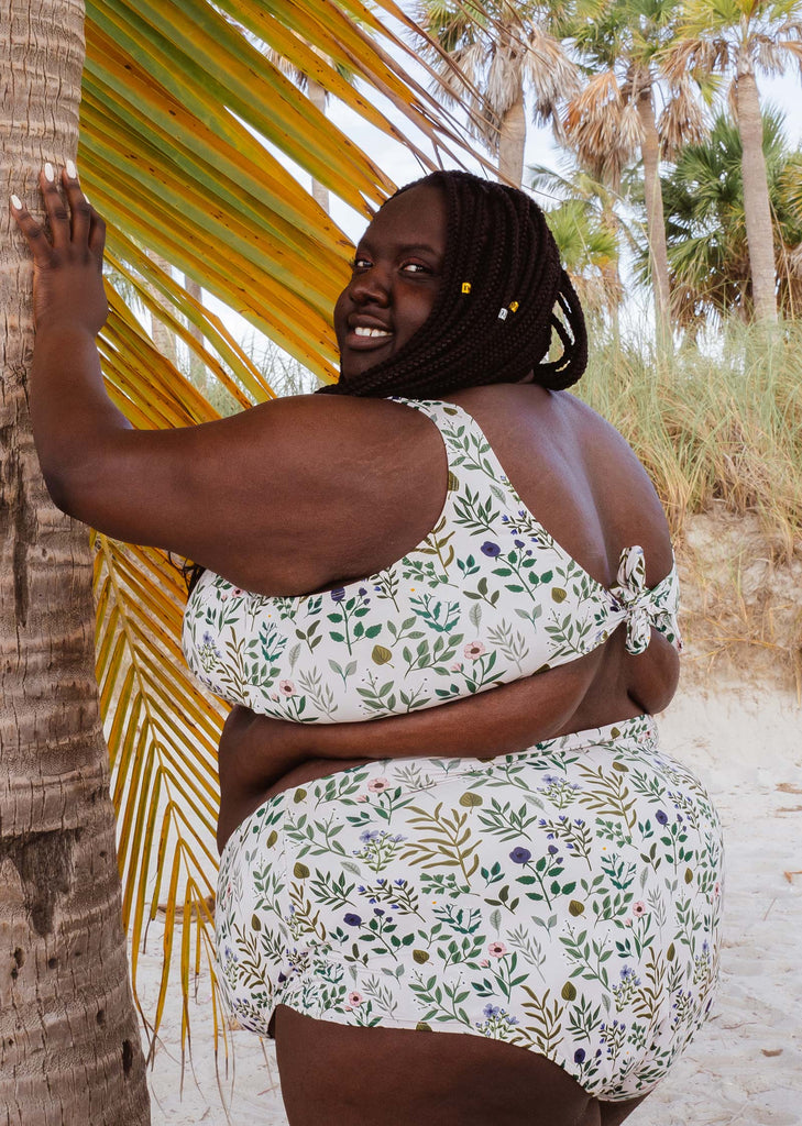 Une femme portant le haut de Bikini Lima Herboria Bralette à côté d'un palmier sur Key Biscayne à Miami.