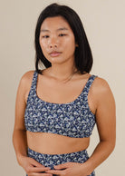 A woman in a blue floral bralette bikini top.