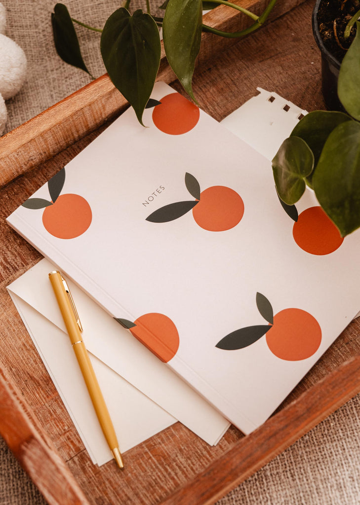 Un Carnet de notes Mimi & August Petites Oranges sur un plateau.