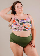 A woman in a Mimi & August Mango Botanica Bralette bikini top with green bottoms posing confidently against a neutral background.