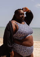 Une femme de grande taille debout sur une plage avec son haut de bikini Mango Moonflower Bralette