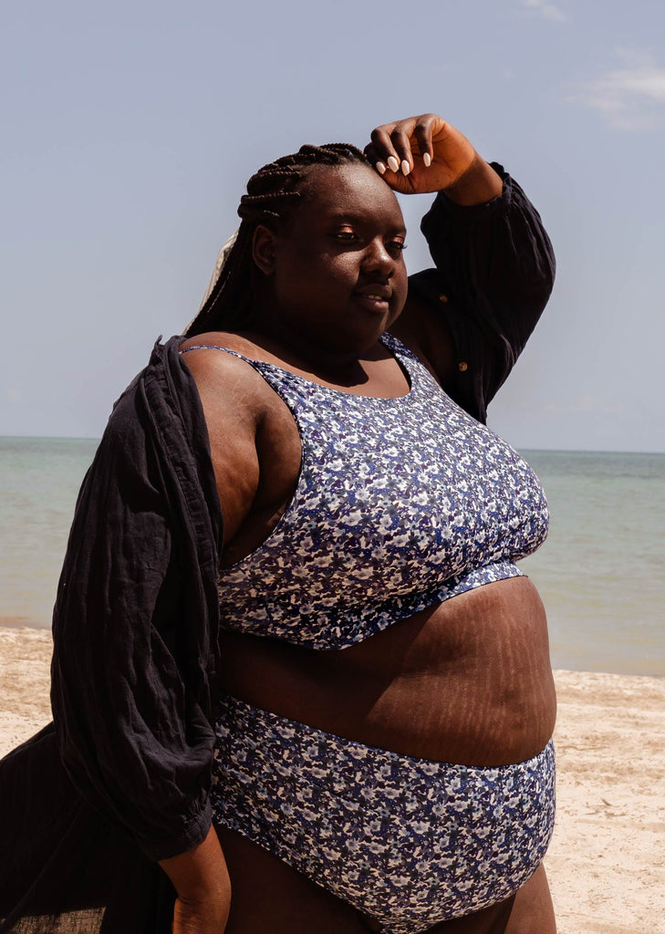 A plus-size woman standing on a beach with her Mango Moonflower Bralette Bikini Top