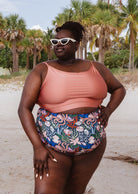 Une femme vêtue d'un haut de bikini Mimi et August Sunset Bralette et d'un bas de bikini à imprimé floral.