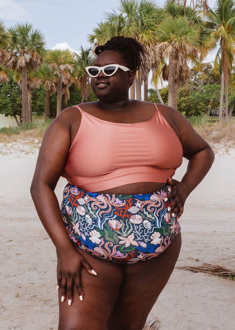 A woman in a Mimi and August Sunset Bralette Bikini Top and floral print bikini bottom