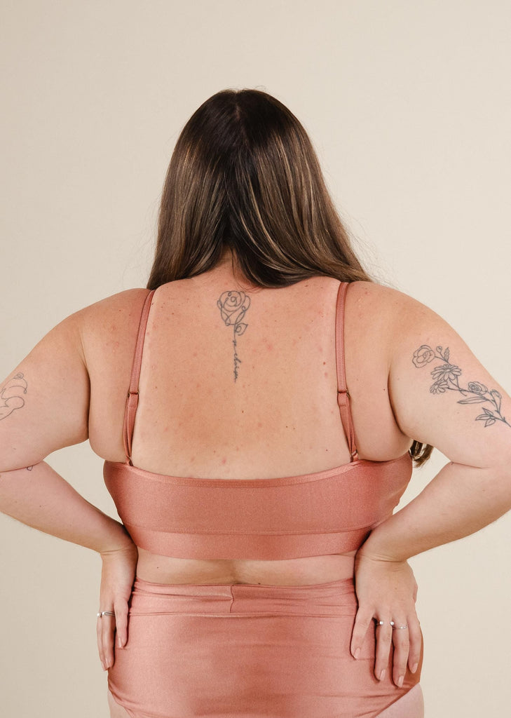 A woman wearing a Mango Sunset Bralette Bikini Top with a rose tattoo on her back.