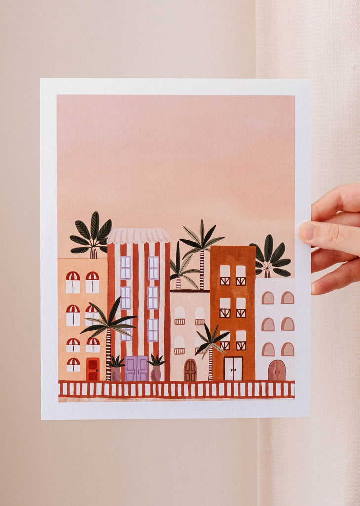 An Miami Art Print of a hand holding a picture of Miami's buildings amidst luscious tropical foliage, by Mimi & August.